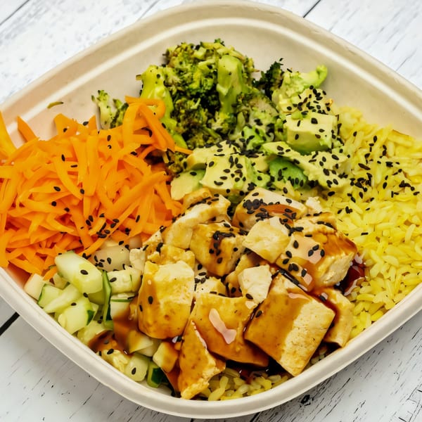 Sprout Mediterranean salad bowl with tofu, broccoli, carrots, avocado, cucumber, and yellow rice.